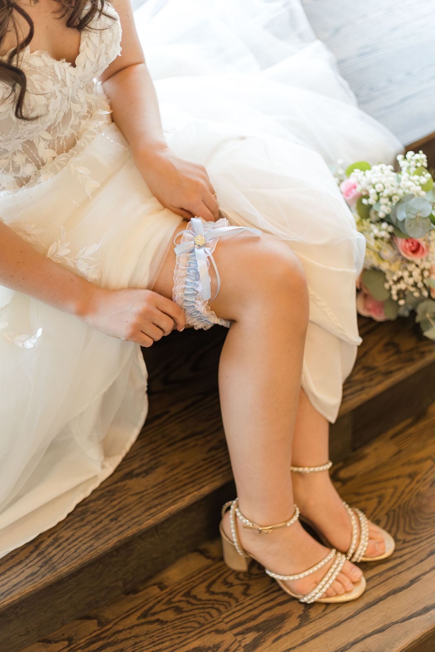 Close-up of a bride's delicate lace wedding dress, hands and elegant bridal accessories during wedding preparations.