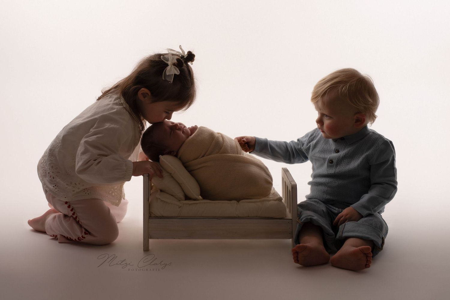 Broertje en zusje met newborn baby in een bedje tijdens een fine art newbornshoot