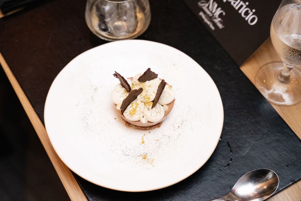 Elegant dessert with whipped cream and chocolate shavings on a white plate at a fine dining restaurant.