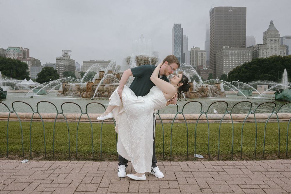 Couple shares romantic dip pose in front of Buckingham Fountain in Chicago on a cloudy wedding day.