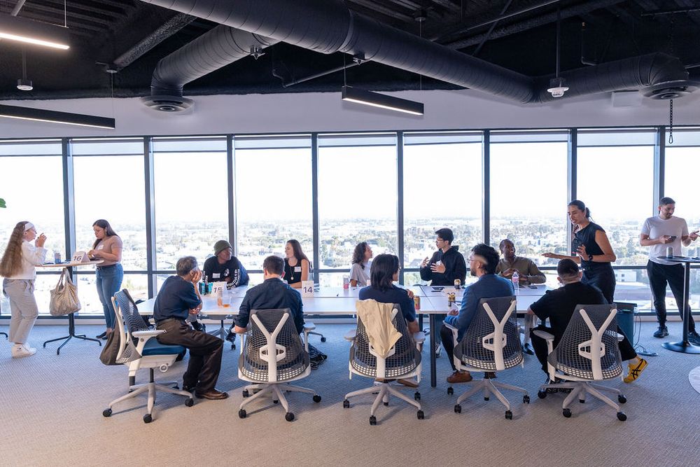 Professionals collaborating around a conference table in a modern high-rise office with panoramic city views.