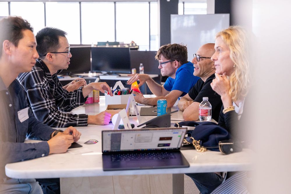Diverse group of professionals engaged in a collaborative meeting around a conference table in a modern office.