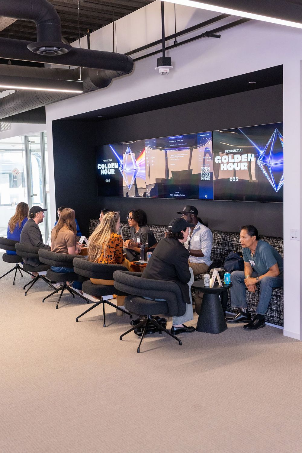 Group of professionals meeting in a modern office lounge with large screens displaying Golden Hour branding.
