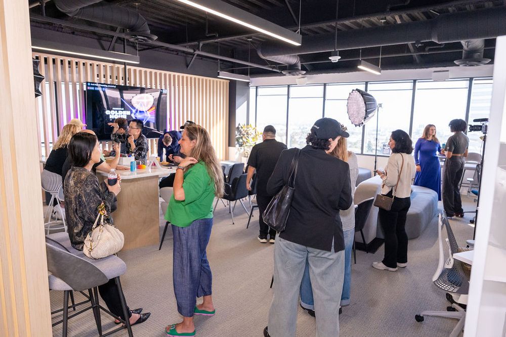 People gather in a modern studio space during a professional photo or video shoot with lighting equipment.
