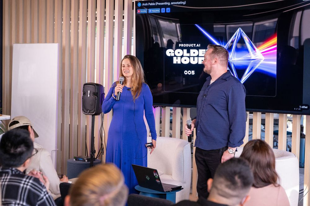 Two speakers present at Golden Hour event 008, woman in blue dress holding microphone on stage.