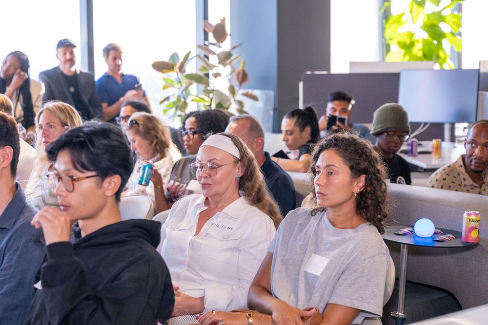 Diverse group of professionals attentively listening at an indoor corporate event or seminar in a modern office space.
