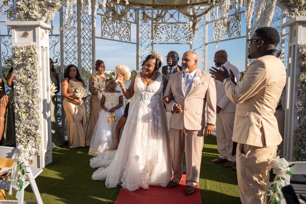 Joyful newlyweds walk down the aisle at an elegant outdoor wedding ceremony with guests celebrating.