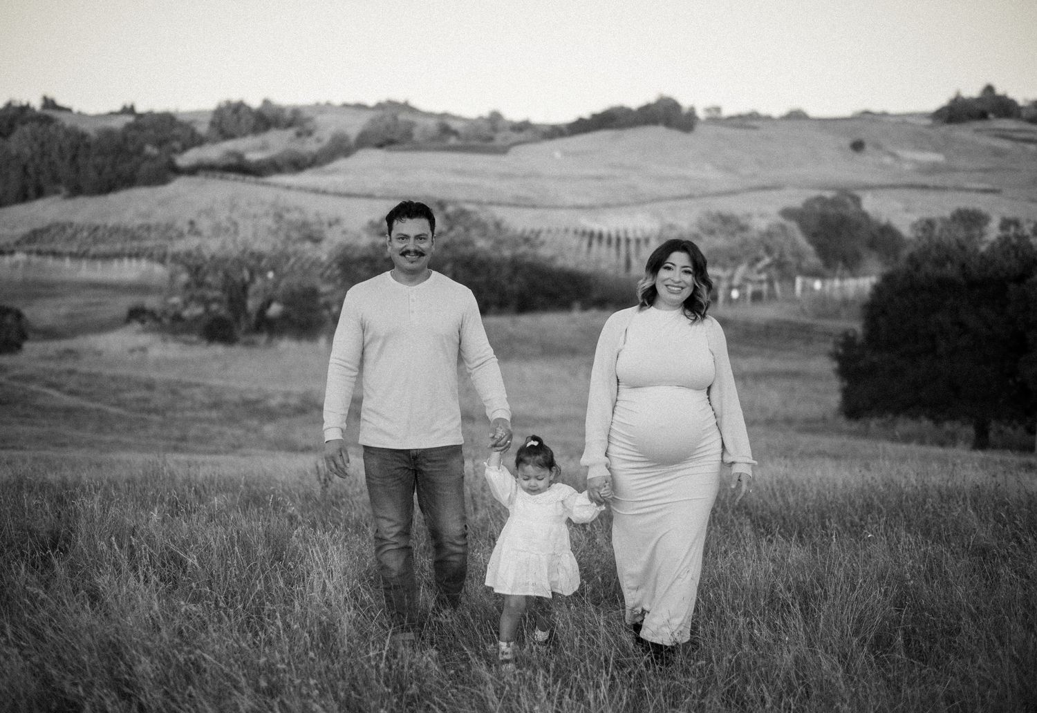 A family laughing and exploring together at Crane Creek, surrounded by open hills, tall grasses, and the beauty of Sonoma County.