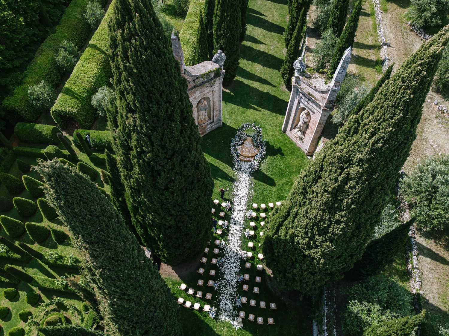Bride in flowing white gown poses near fountain outside French chateau.