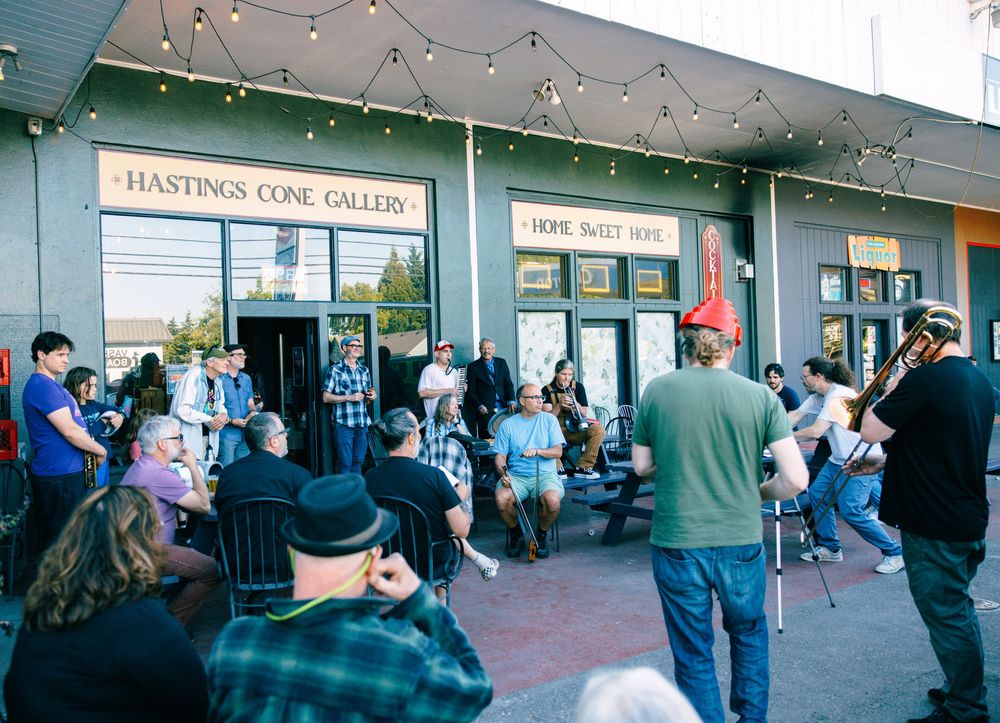 Crowd gathers outside Hastings Cone Gallery for a live music event on a sunny day.
