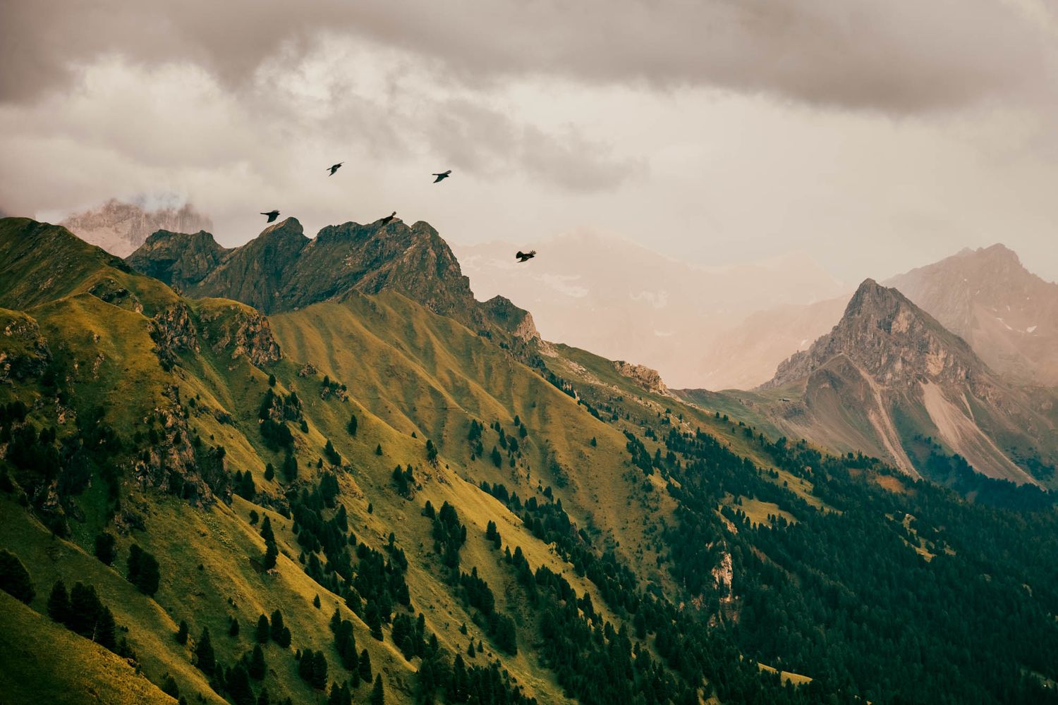 Dramatic Dolomite mountains with jagged rocky peaks, winding road, and moody overcast sky in the Italian Alps.