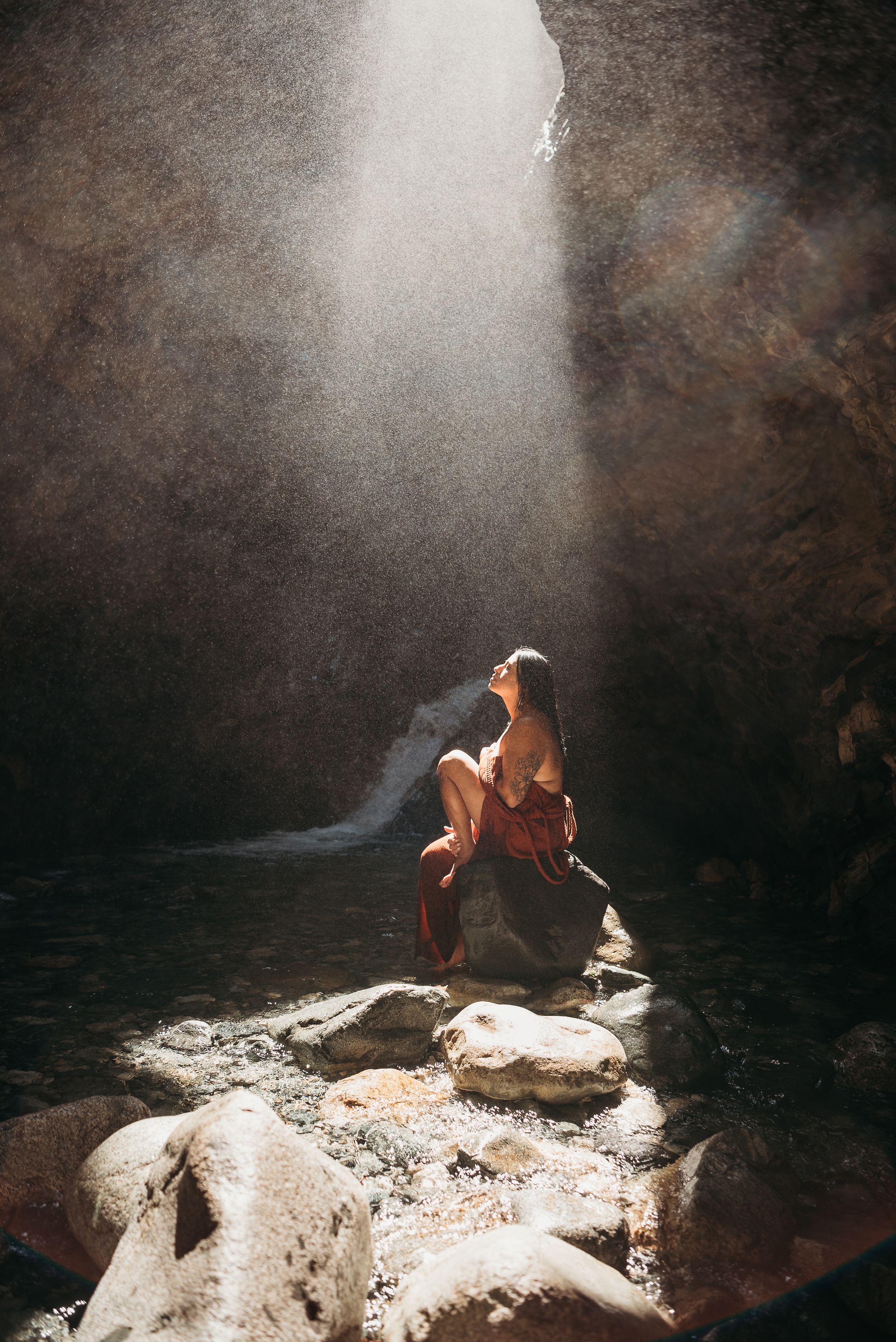 woman sitting under the light of a waterfall in Colorado
