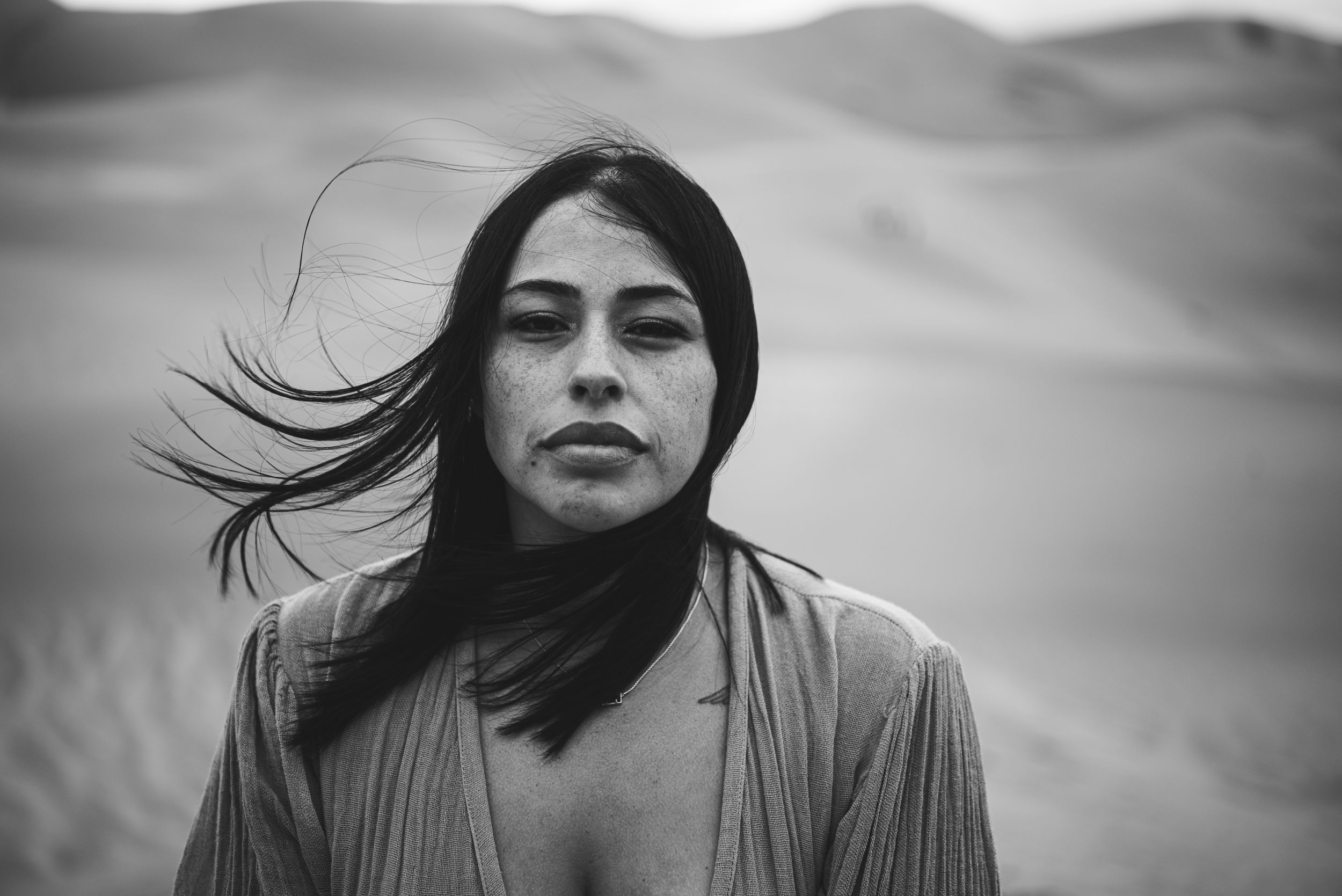 Close up of woman's face with hair blowing off to the side at The Great Sand Dunes in Colorado.