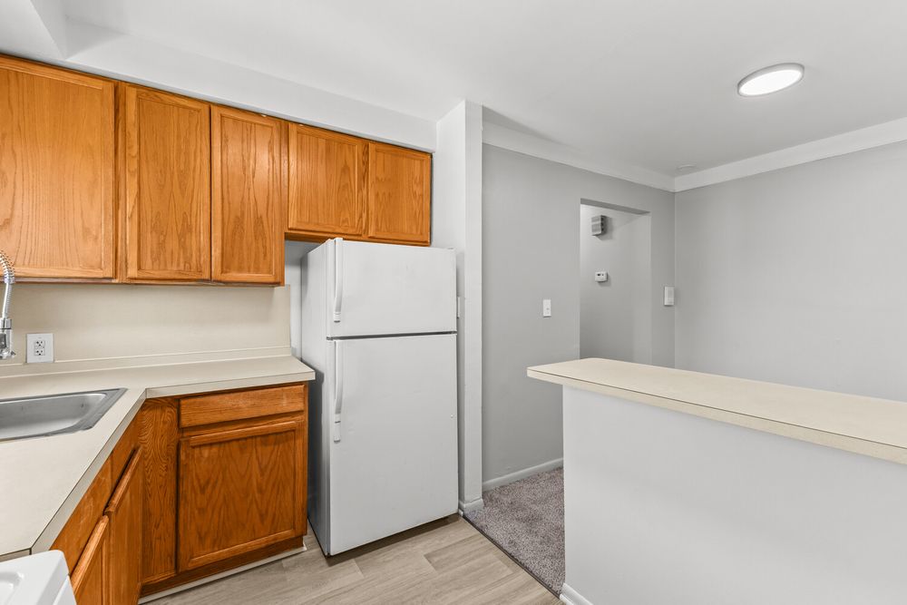 Kitchen featuring oak cabinets, white refrigerator, crown molding, and light wood flooring.