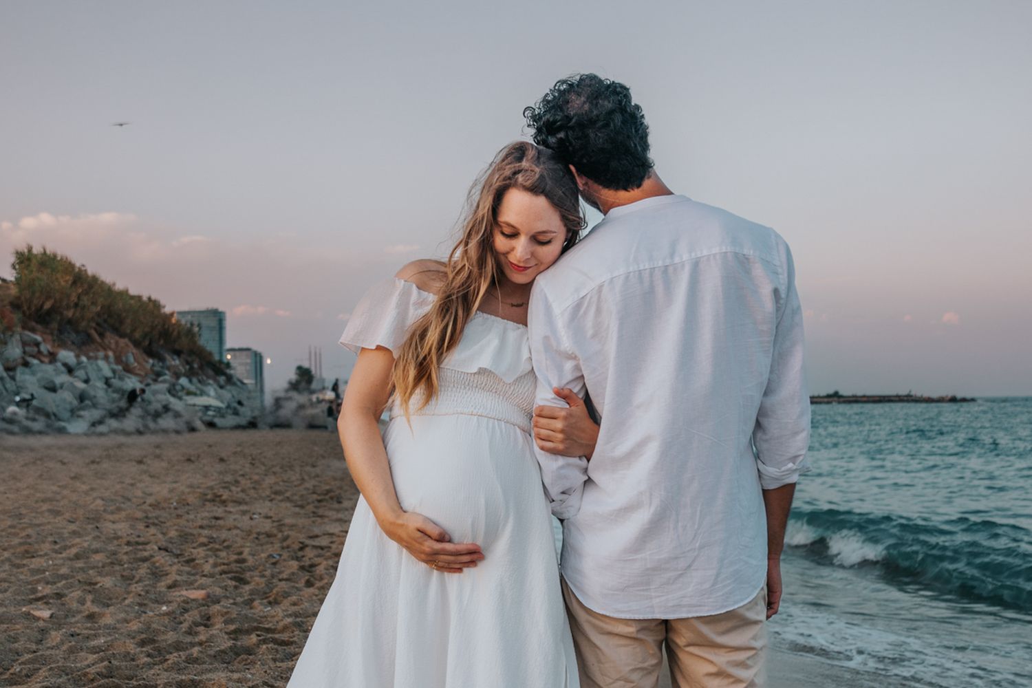 Expectant couple relaxing on poble nou Beach during a beautiful sunset maternity photoshoot in Barcelona