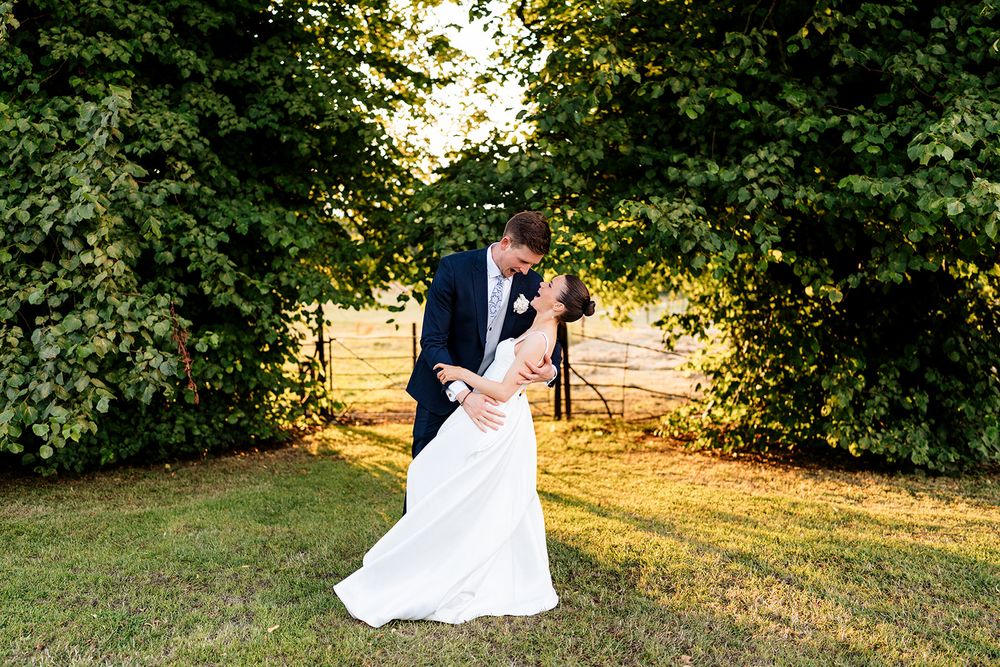 A romantic dip pose during golden hour sunset in a garden setting with lush greenery surroundings.