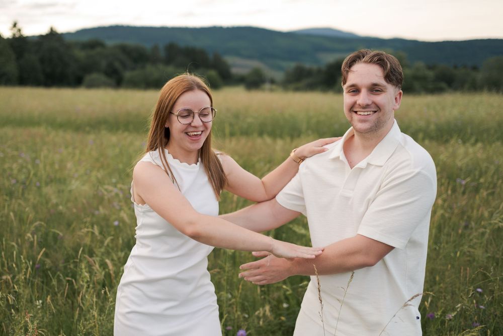Séance engagement en Alsace avec un couple entouré de hautes herbes et de papillons.