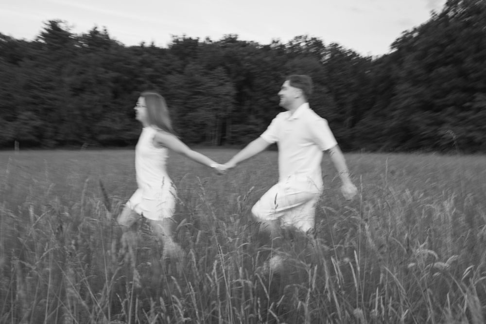 Jeune couple marchant dans les hautes herbes lors d'une séance engagement.
