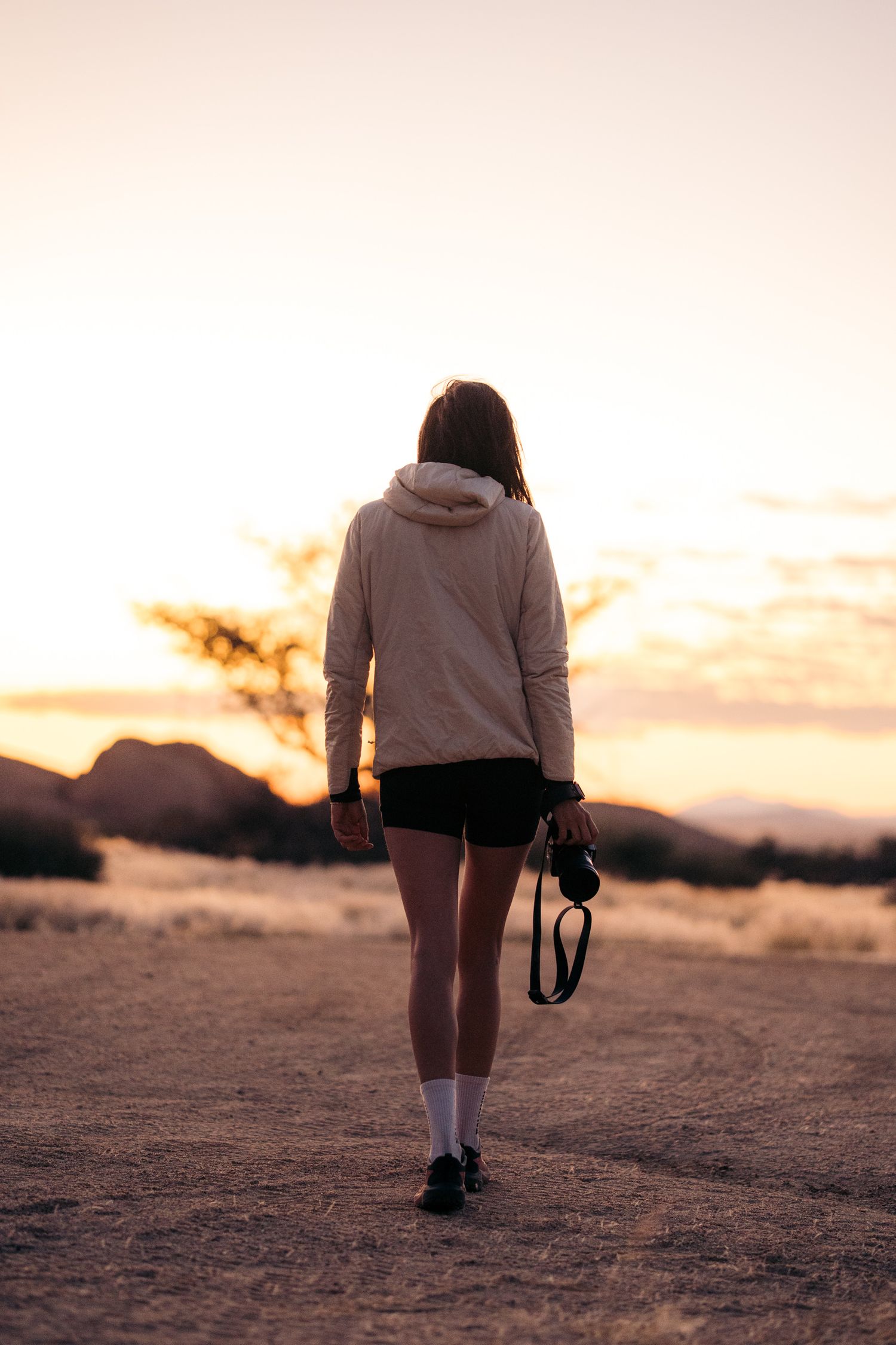 marie blauwart photographe marche de dos dans la savane de namibie au coucher du soleil
