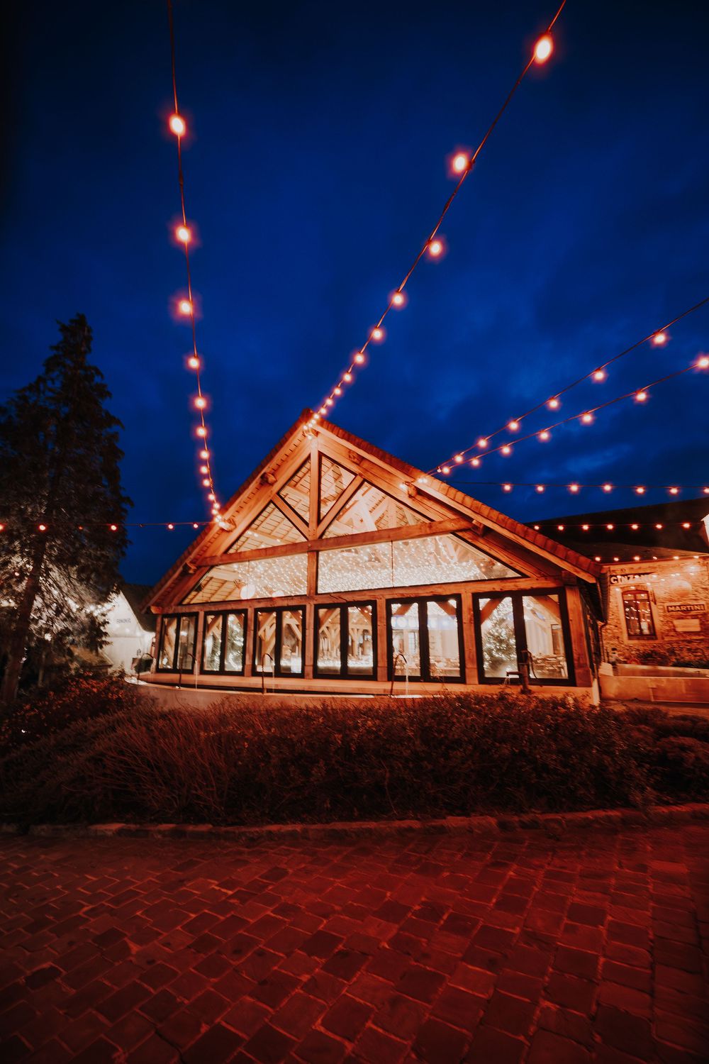 Rustic wedding venue barn with warm string lights glowing against a deep blue twilight sky.