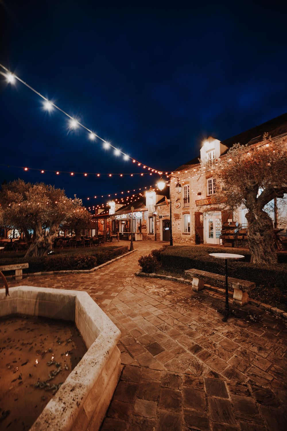 Charming stone courtyard venue at night with string lights and rustic architecture creating a warm romantic ambiance.