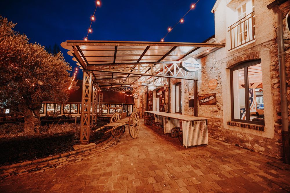 Charming outdoor venue patio with string lights illuminating stone walls and pergola at night.