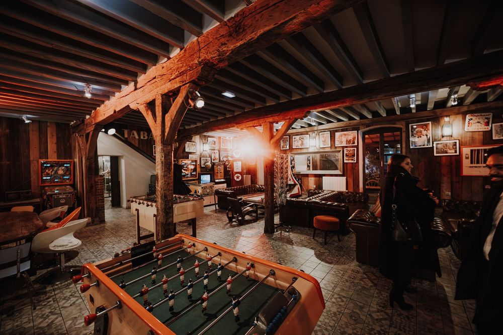 Rustic wedding venue game room featuring a foosball table and warm wooden beam interior decor.