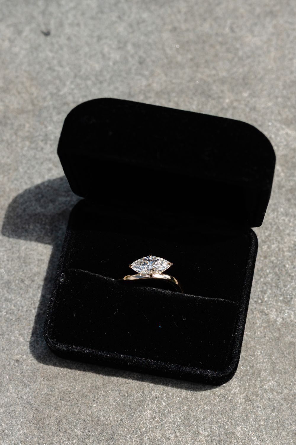 Marquise diamond solitaire engagement ring displayed in a black velvet ring box.
