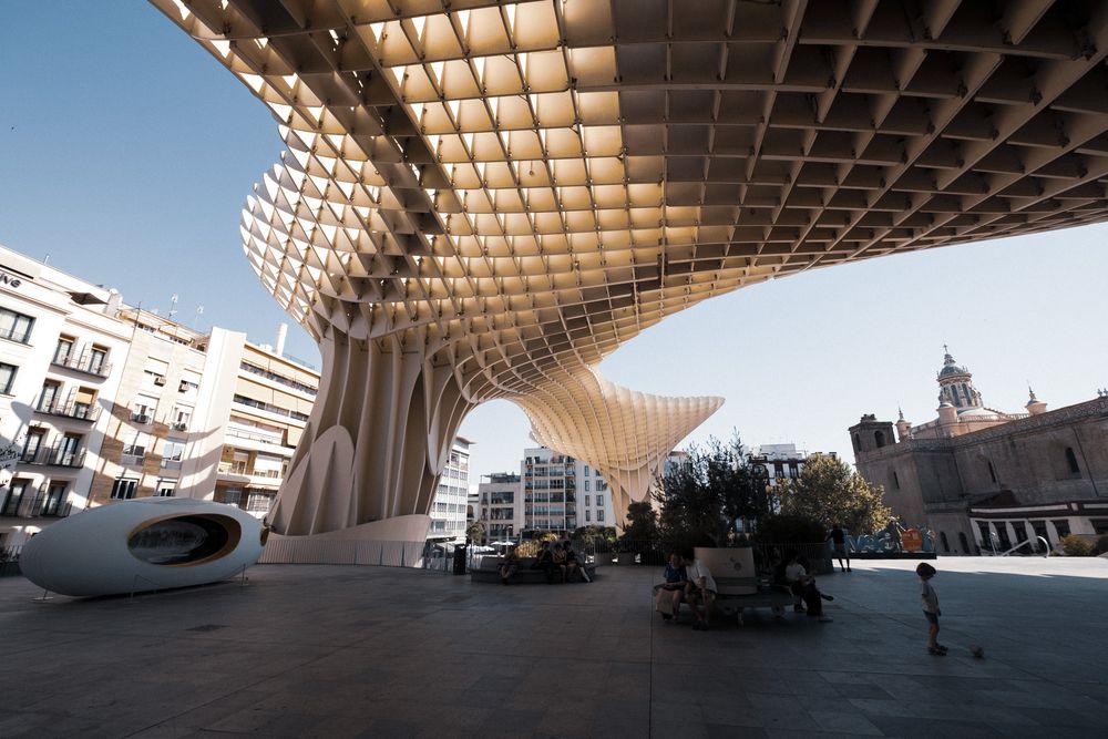 Close-up view of the Metropol Parasol structure in Seville, Spain, featuring its distinctive latticed wooden canopy against a blue sky.