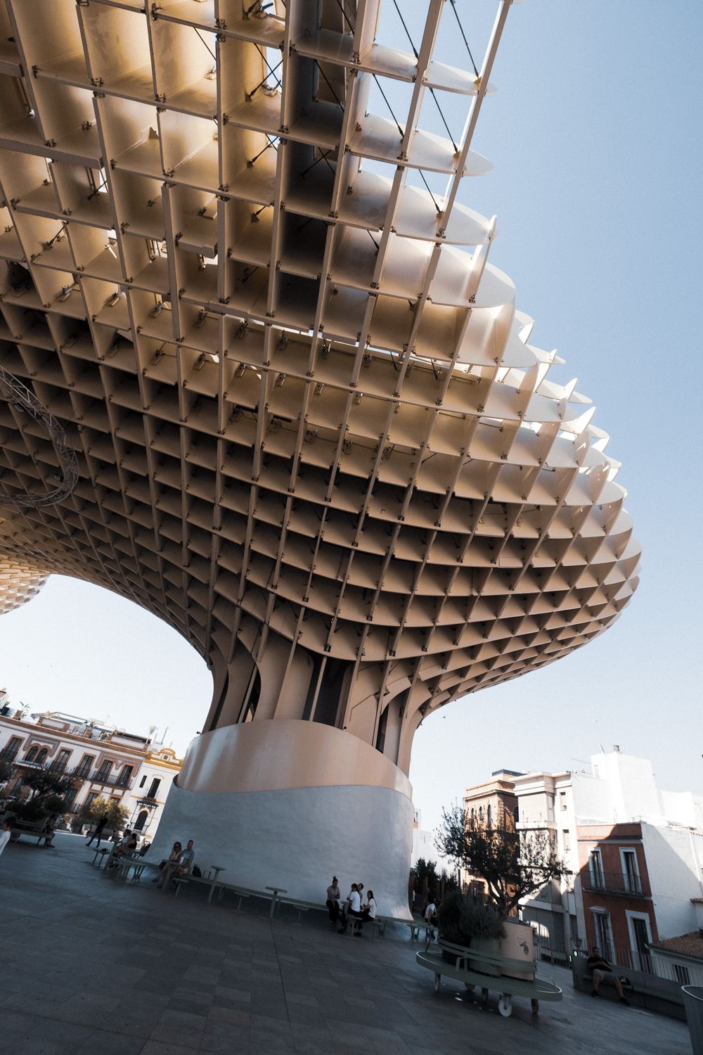 Close-up view of the Metropol Parasol structure in Seville, Spain, featuring its distinctive latticed wooden canopy against a blue sky.