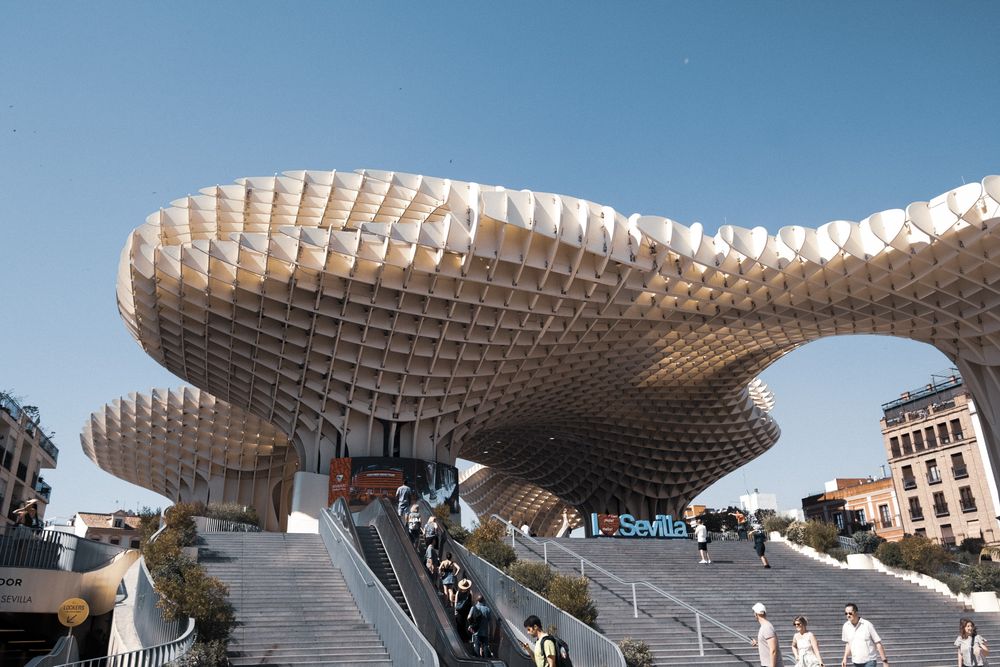 Close-up view of the Metropol Parasol structure in Seville, Spain, featuring its distinctive latticed wooden canopy against a blue sky.
