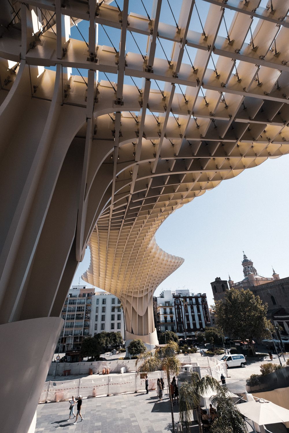 Close-up view of the Metropol Parasol structure in Seville, Spain, featuring its distinctive latticed wooden canopy against a blue sky.