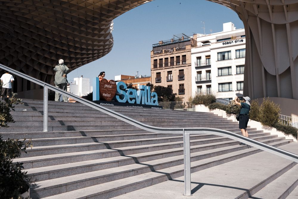 Close-up view of the Metropol Parasol structure in Seville, Spain, featuring its distinctive latticed wooden canopy against a blue sky.