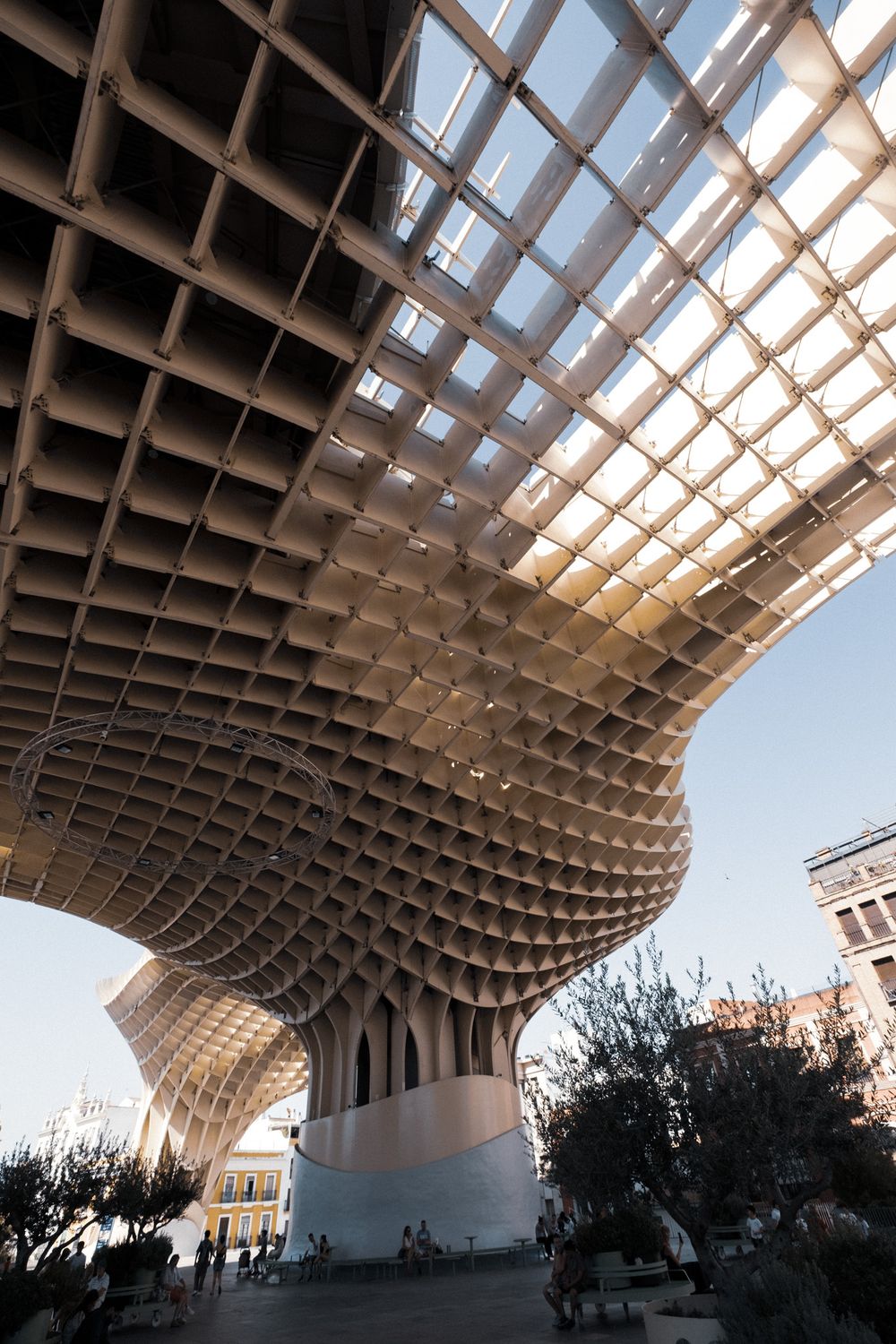 Close-up view of the Metropol Parasol structure in Seville, Spain, featuring its distinctive latticed wooden canopy against a blue sky.