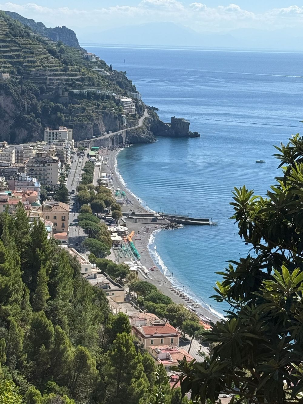 Panoramic view of a curved beach and coastal town along the stunning Amalfi Coast with turquoise waters.
