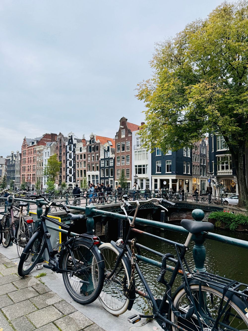 Bicycles parked on a canal bridge with colorful Dutch townhouses lining the waterway in Amsterdam.