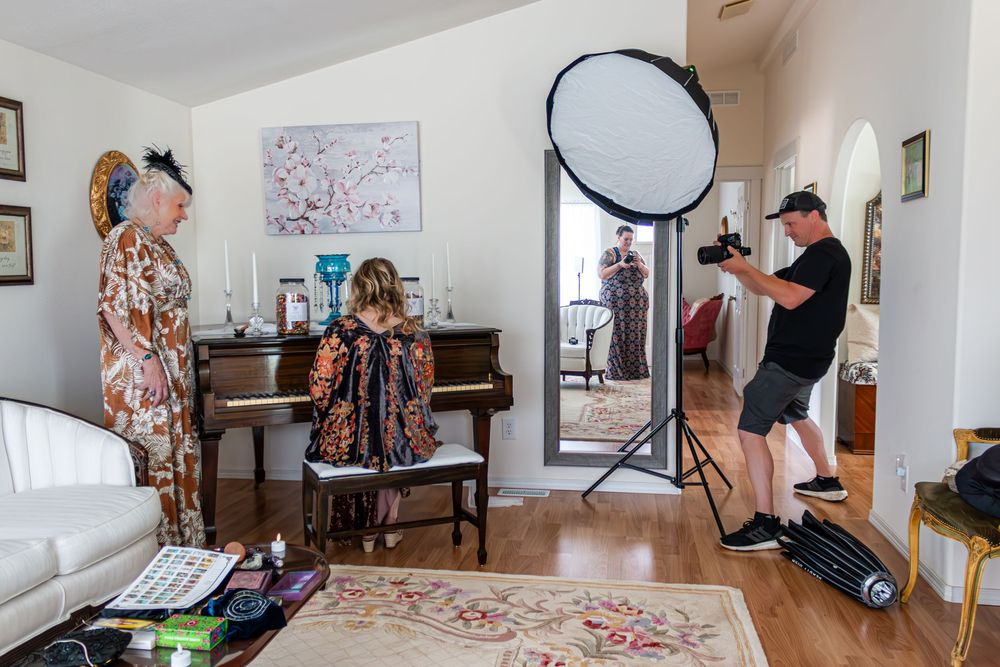 Behind the scenes of a home photo shoot with photographer, models, and studio lighting equipment.