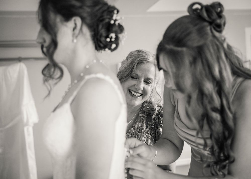 Black and white photo of bride sharing an emotional moment with bridesmaids while getting ready.