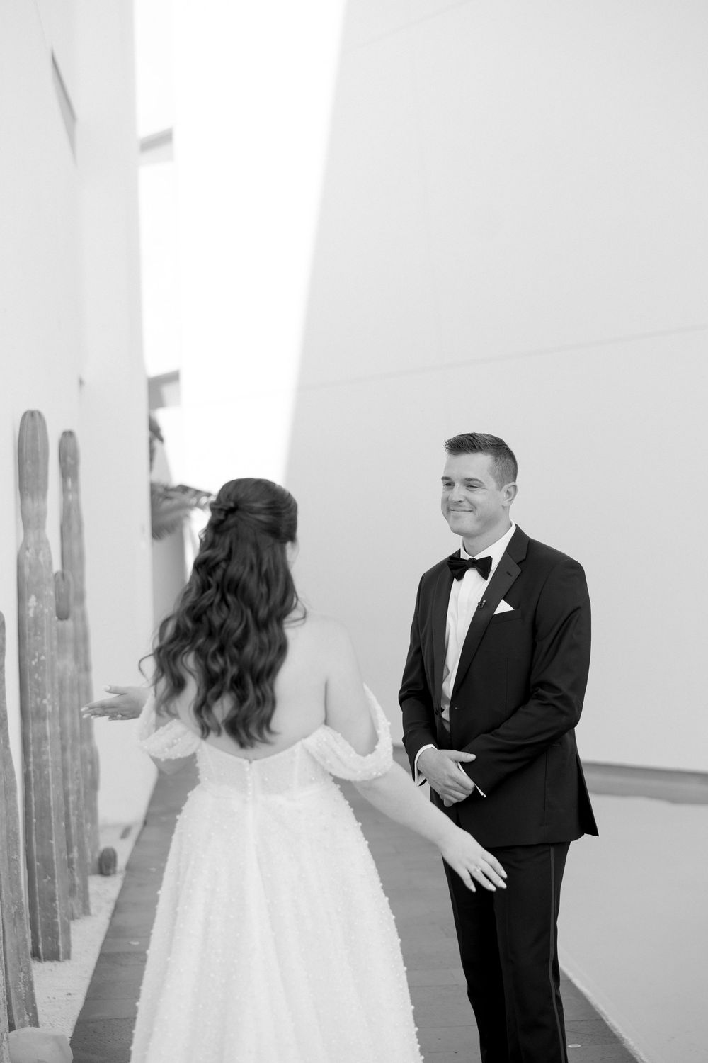 A groom in a tuxedo smiles at his bride during a first look moment at their wedding.