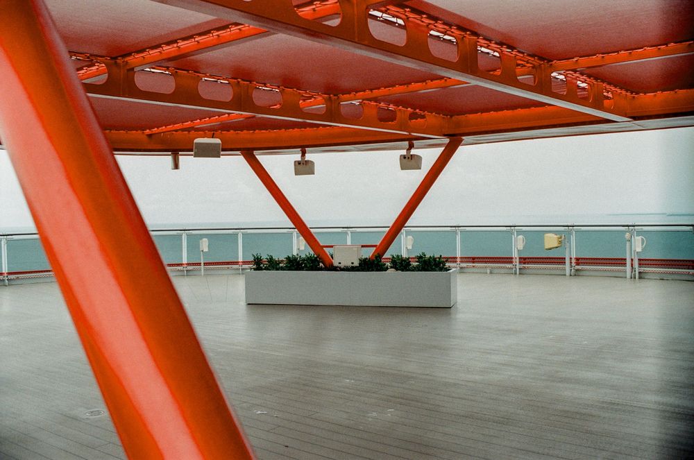 Open deck area with bold red steel structural beams and a central white planter box overlooking the ocean.