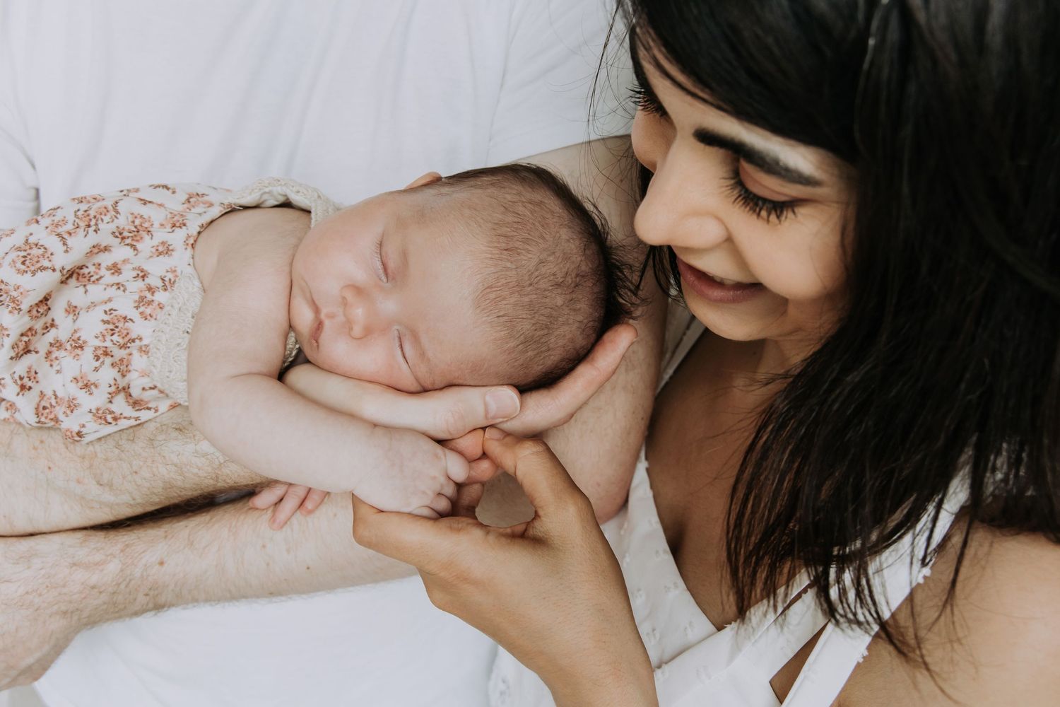 Parents admiring and gently holding their newborn baby during an in-home lifestyle newborn photography session.