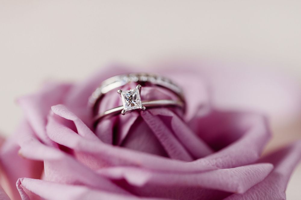 Diamond engagement ring and wedding band nestled inside a soft pink rose bloom.