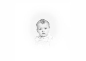 Black and white vintage portrait photo of a baby with short hair wearing a white outfit, looking at the camera.