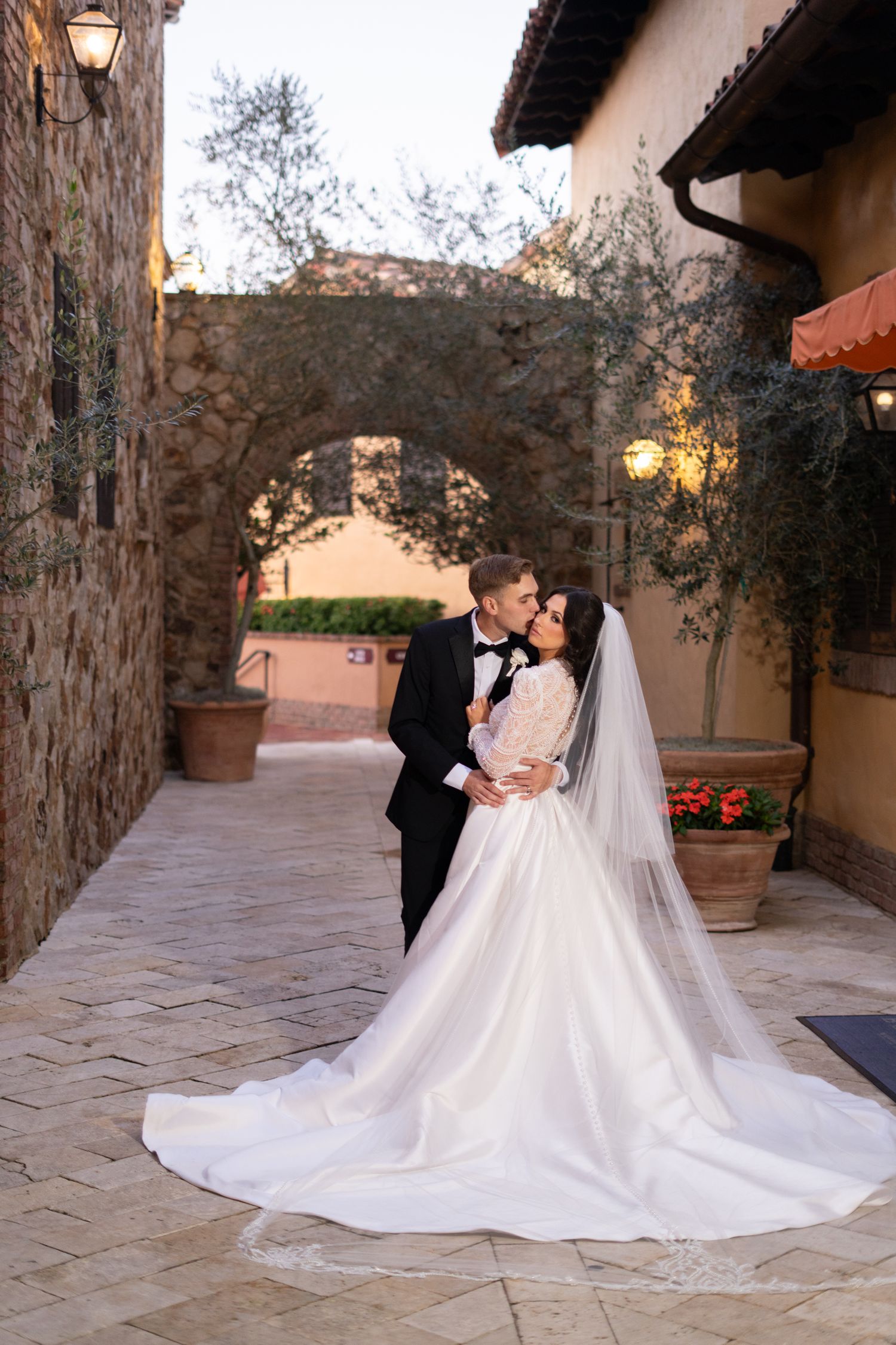 Bride and groom romantic kiss portrait Bella Collina stone archway Montverde Florida Weddings by Ray