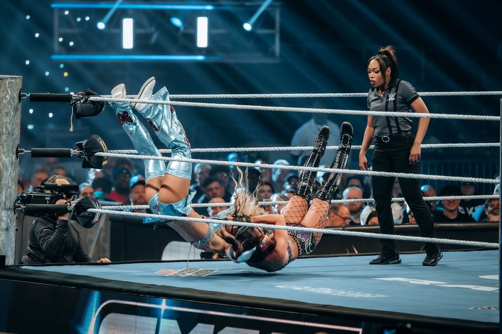 Two wrestlers compete in a WWE ring, one pinning the other to the mat while a referee watches closely during a live event.