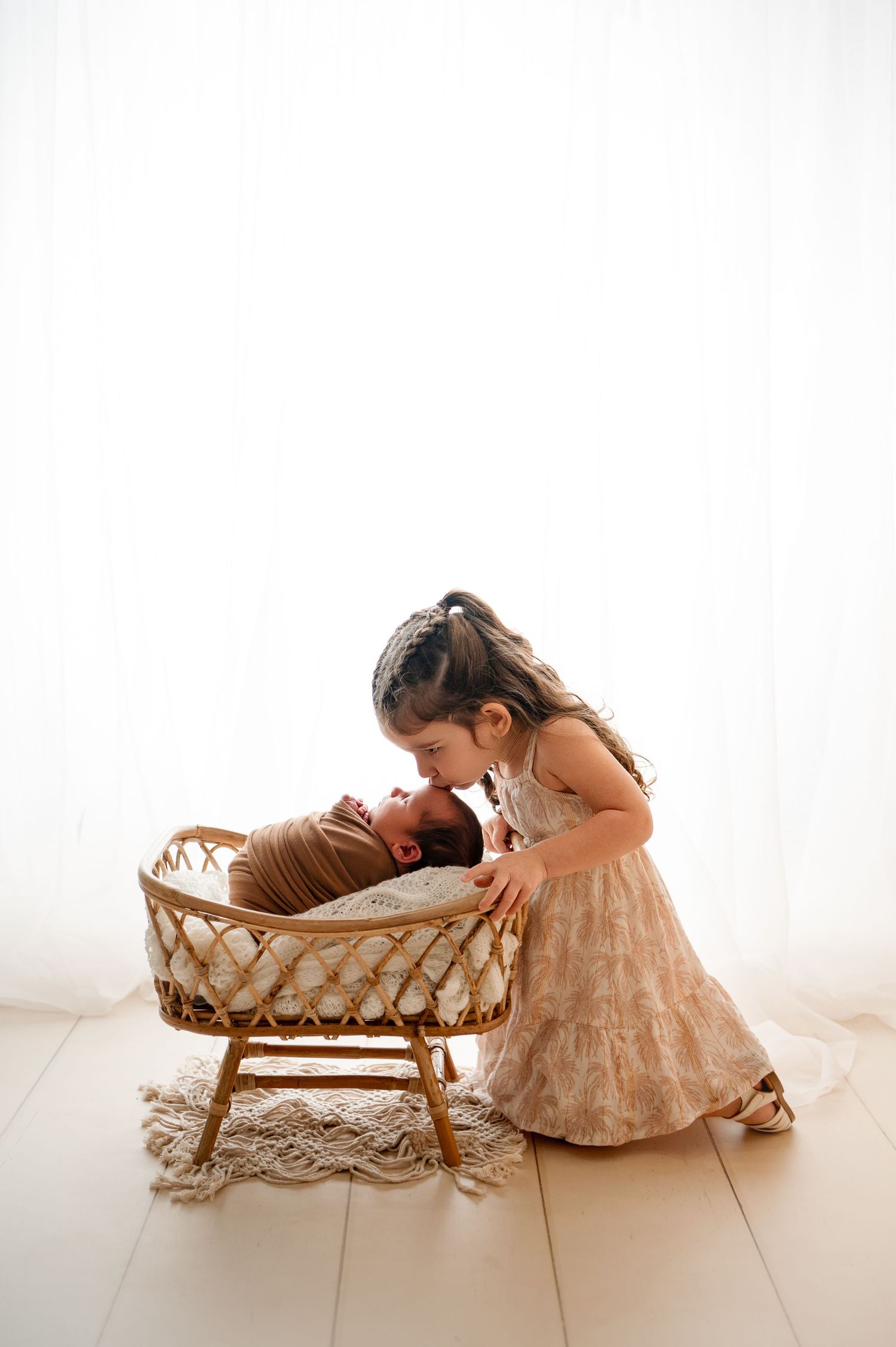 Sleeping newborn baby in olive green ribbed romper with fists raised, posed on matching green backdrop.