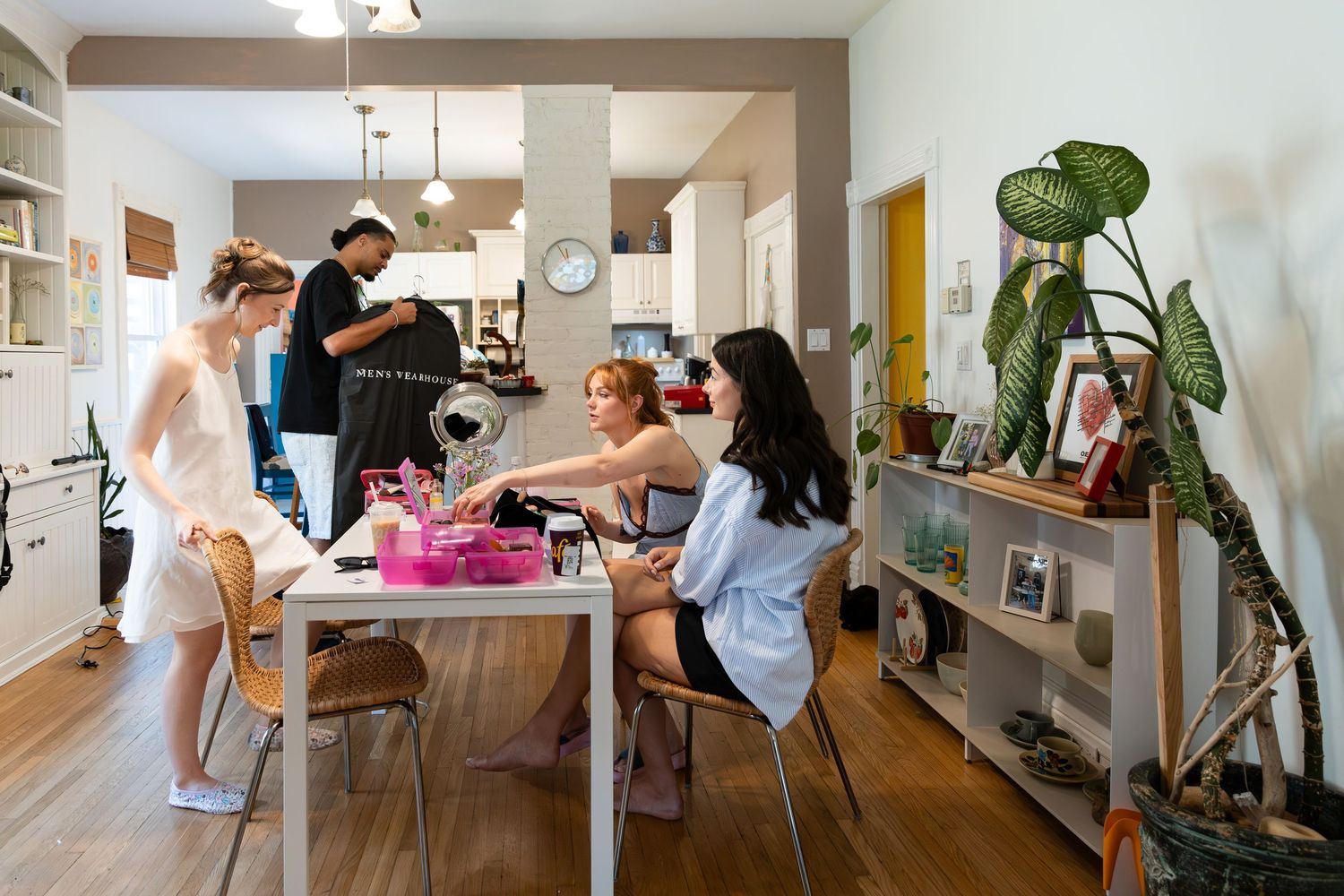 Bride sitting at a table with her friends getting ready to finish her makeup on the morning of her wedding in london, ontario.