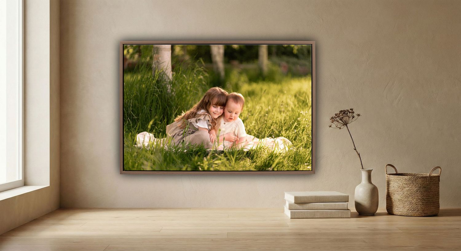 Two young children sitting together in lush green grass, displayed as a framed canvas print on a neutral wall.