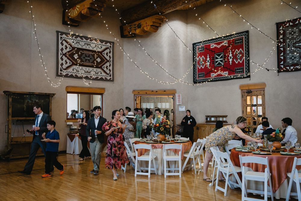 Wedding guests mingle and dance in a rustic hall adorned with Native American tapestries and string lights at Nature Pointe Wedding Venue