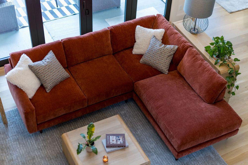Aerial view of rust orange sectional sofa with gray pillows in a bright modern living room.